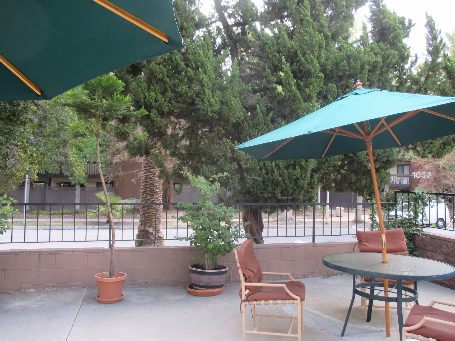 Outdoor patio at Del Mar Park with tables, chairs, and green umbrellas.