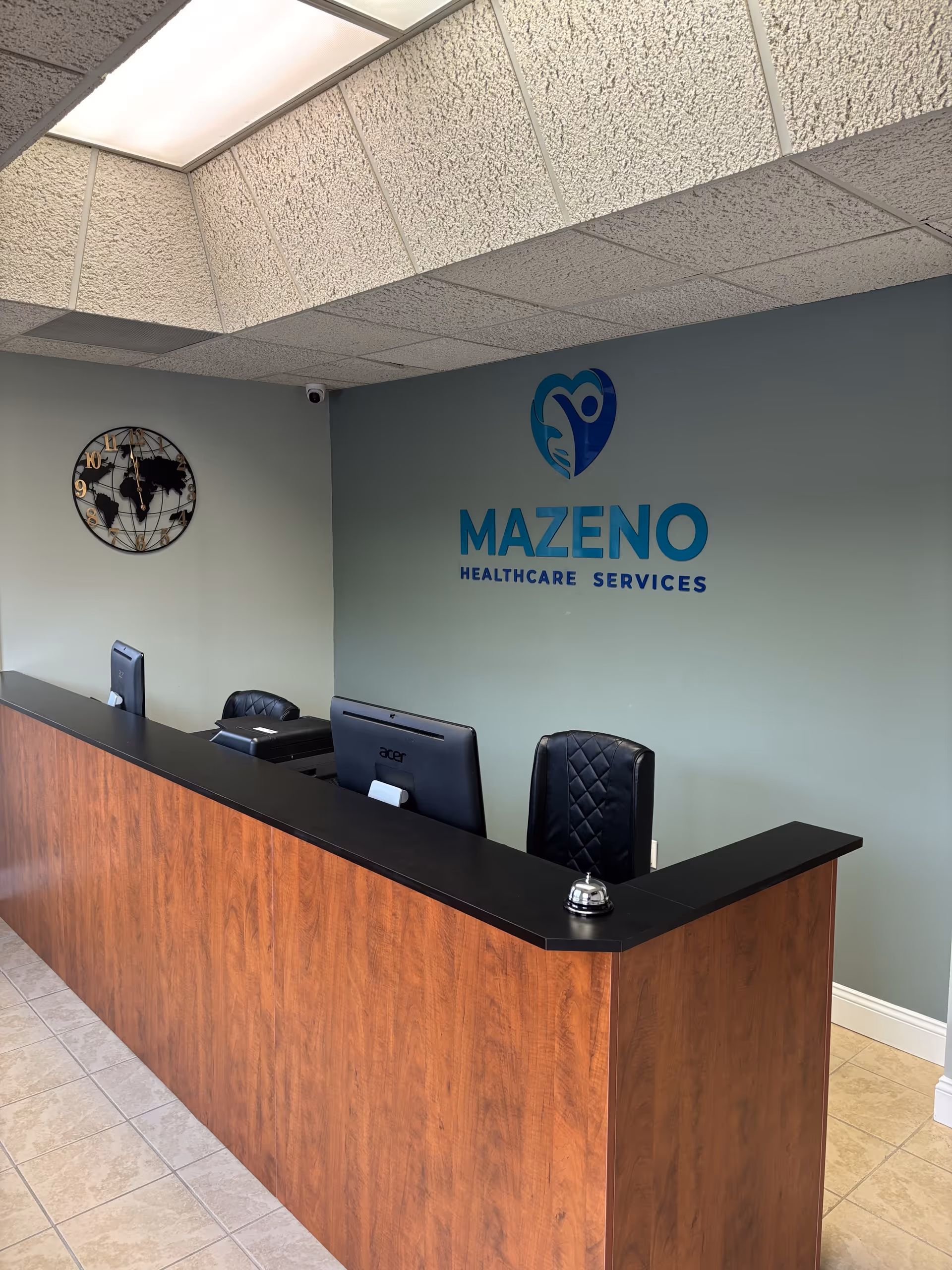 Reception desk inside Mazeno Healthcare Services with computers and a wall logo