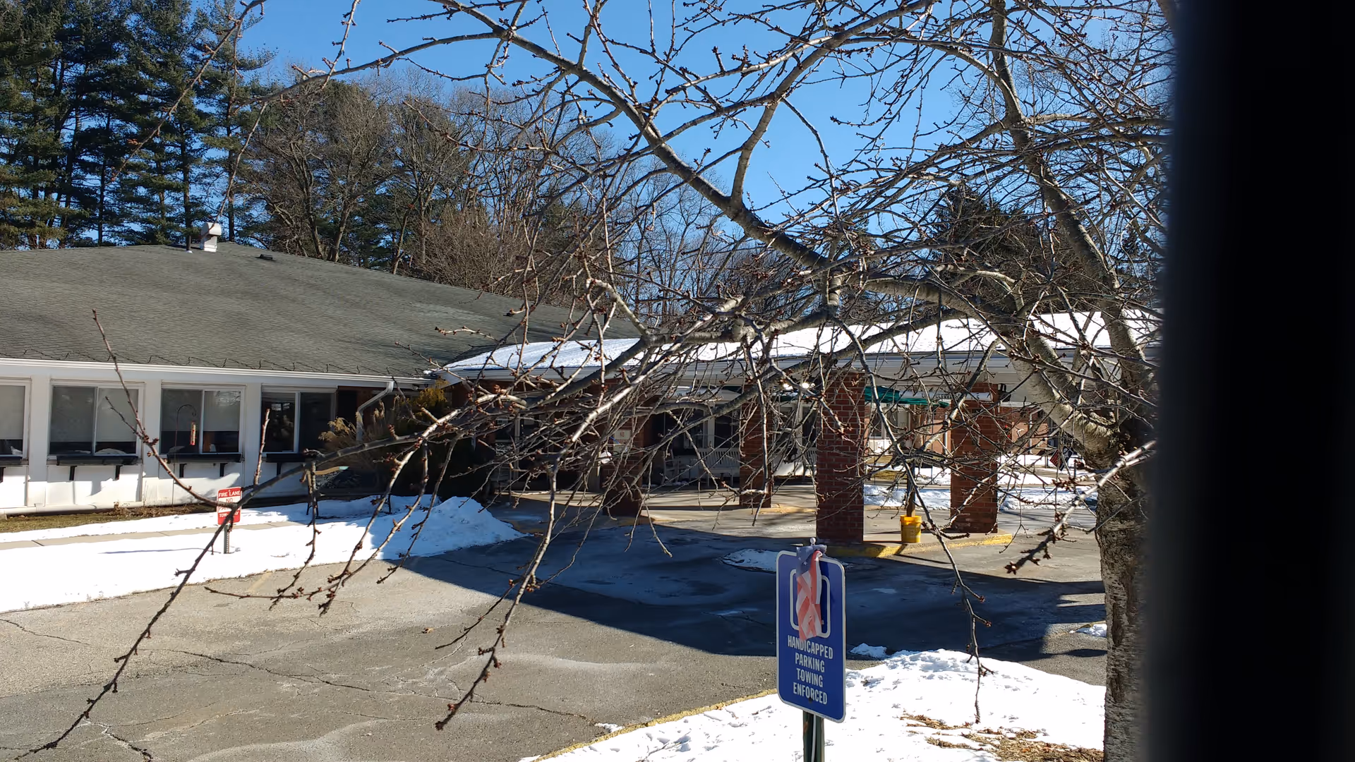 Exterior view of a single-story senior living facility with a snow-covered parking area