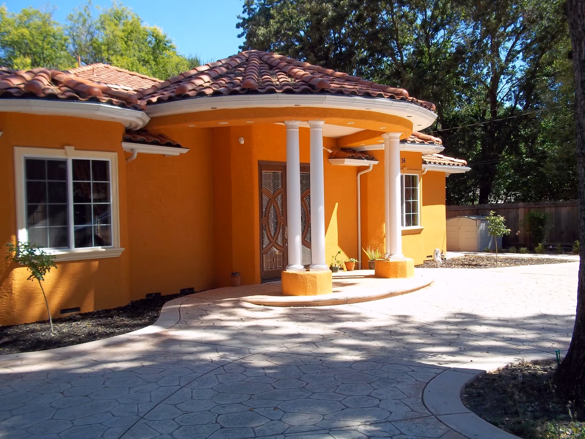 Orange building with a rounded entrance, white columns, and a tiled roof.