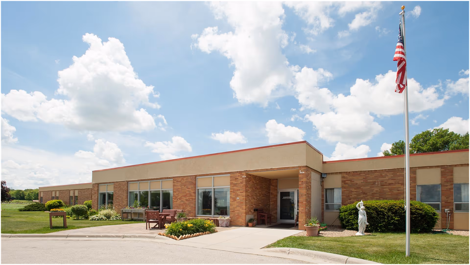 Single-story brick care center exterior with large windows, flagpole, and landscaped entrance.