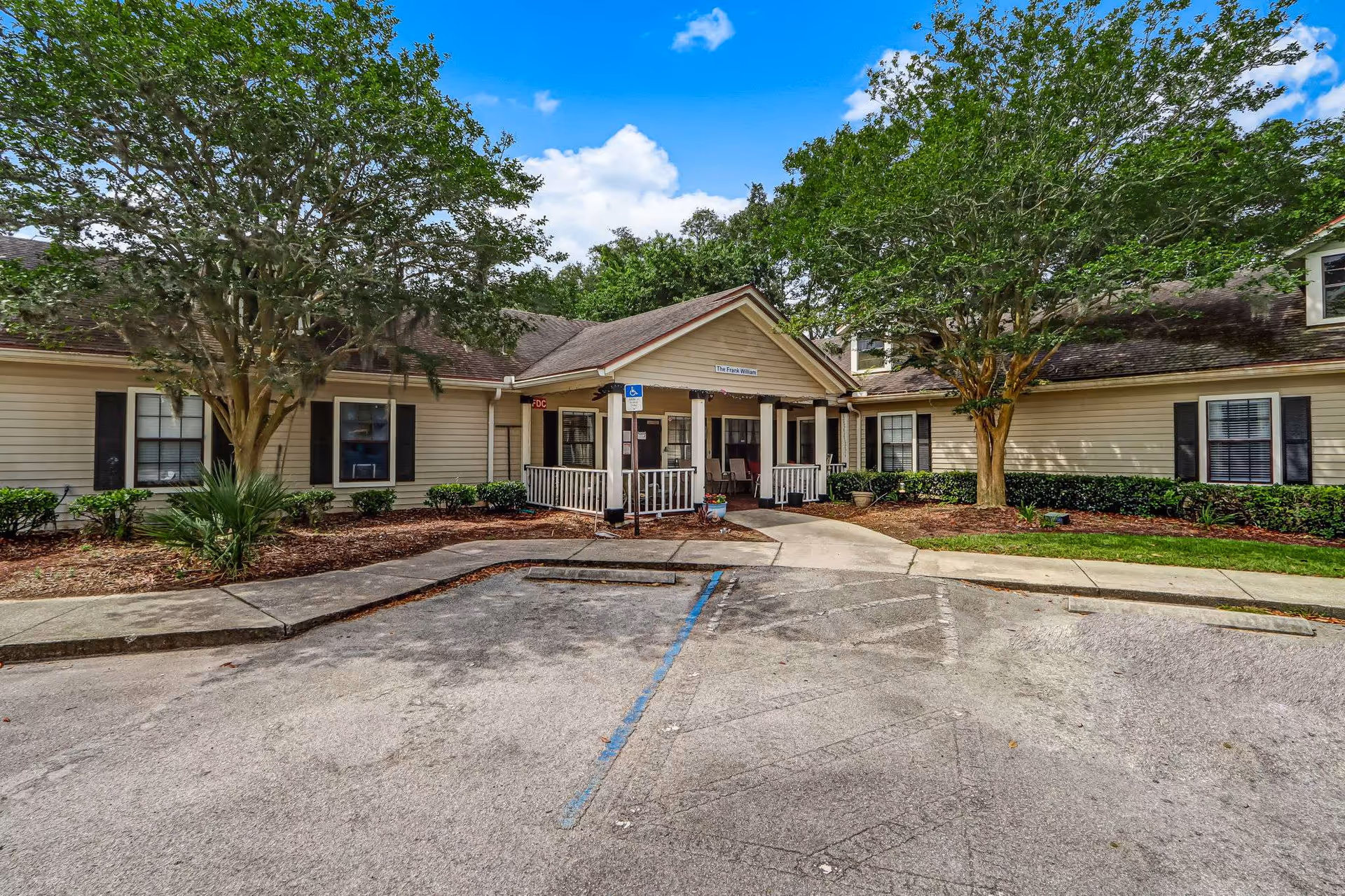 Exterior view of Amelia Springs Assisted Living entrance with landscaping and trees