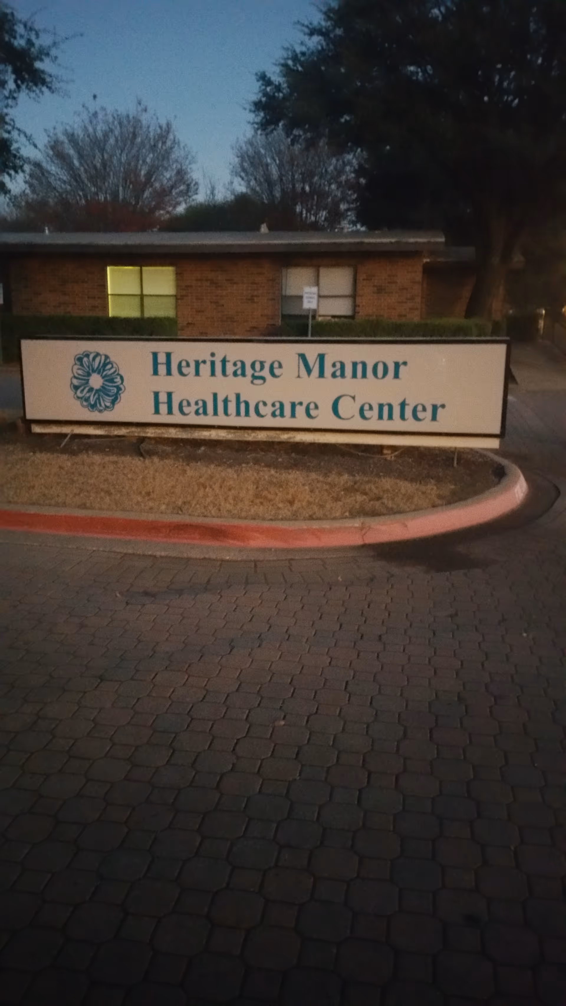 Outdoor sign displaying Heritage Manor Healthcare Center in front of a brick building.