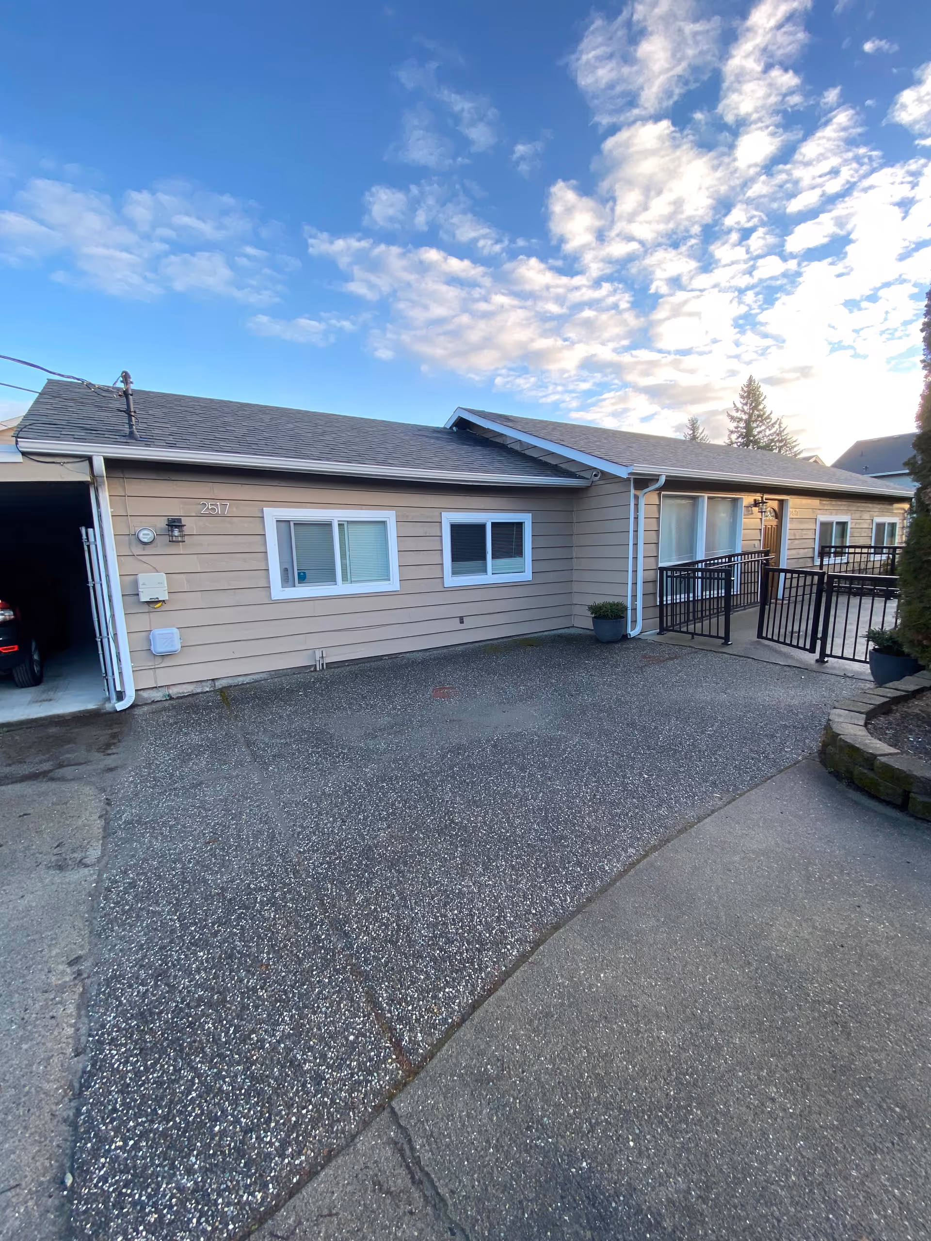 Single-story beige senior home exterior with driveway, railing, and entrance pathway