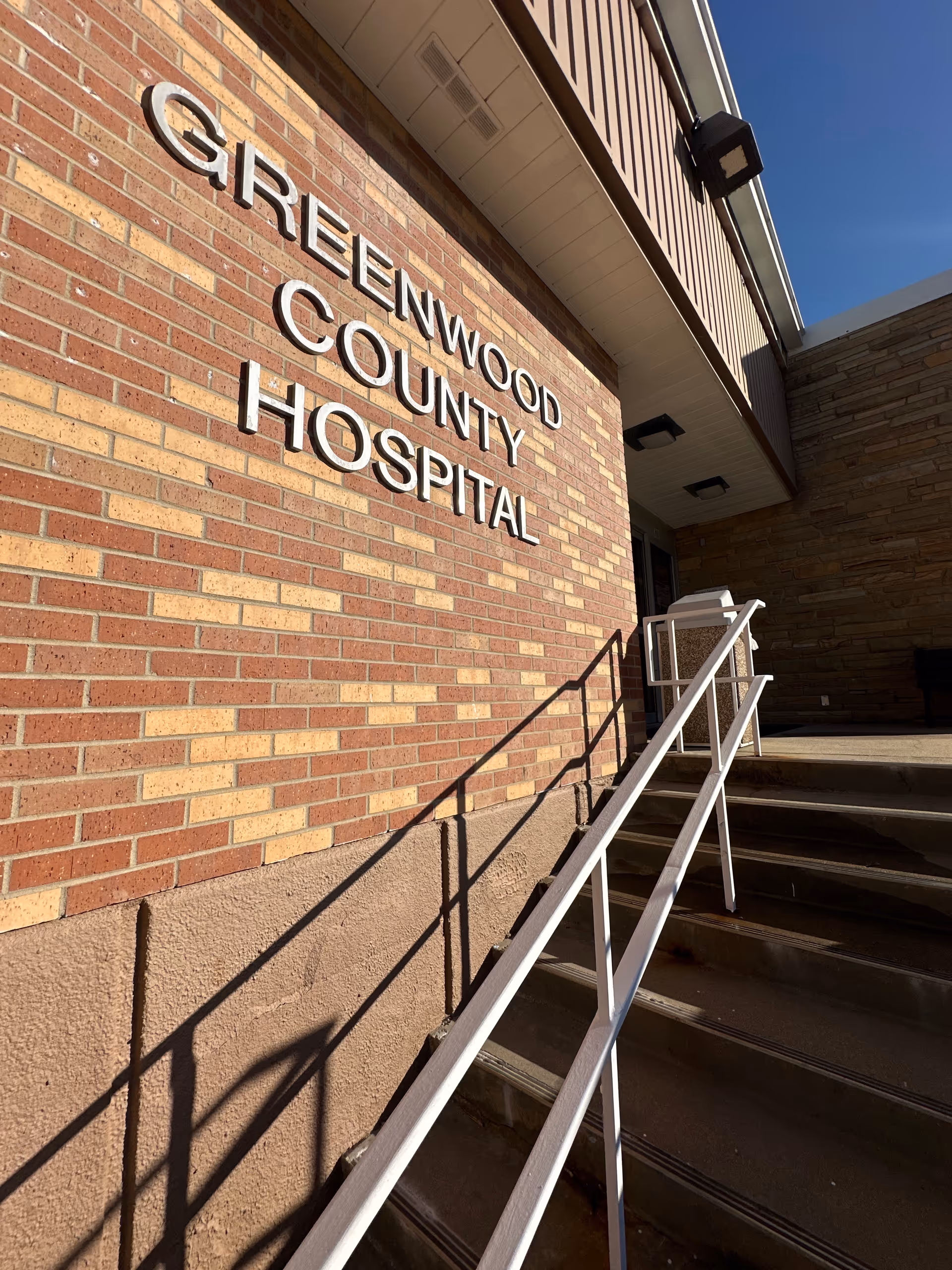 Exterior view of Greenwood County Hospital entrance with brick facade and handrails