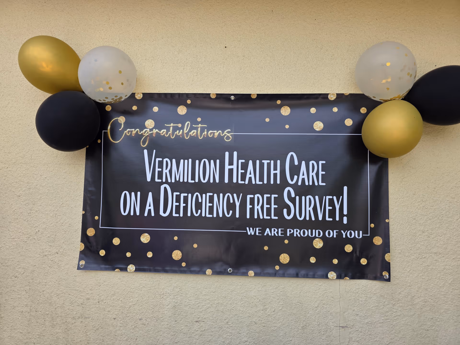 Exterior wall with a congratulatory banner and balloons celebrating a deficiency-free survey.