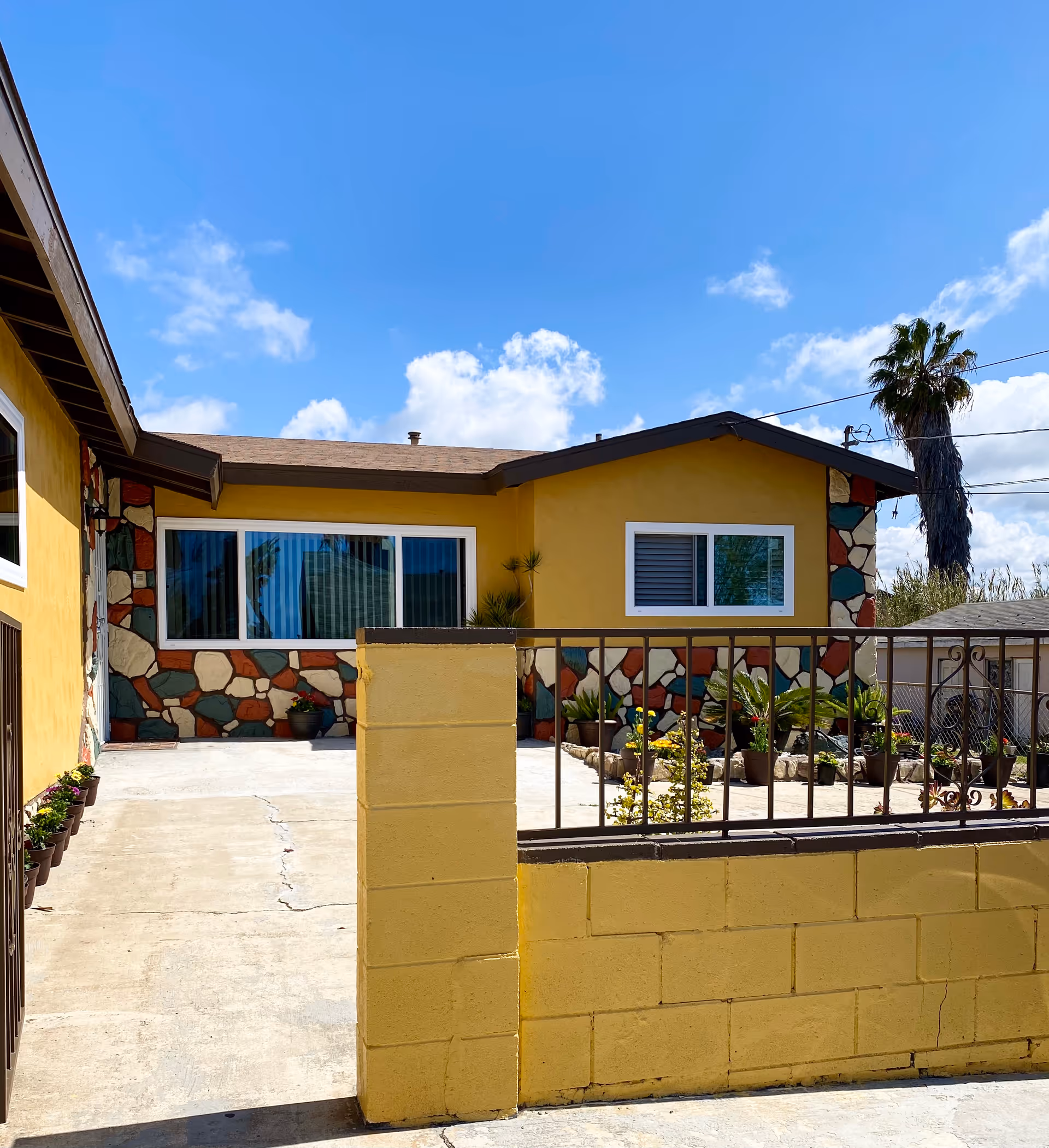 Yellow, single-story building with stone accents and a small front courtyard.