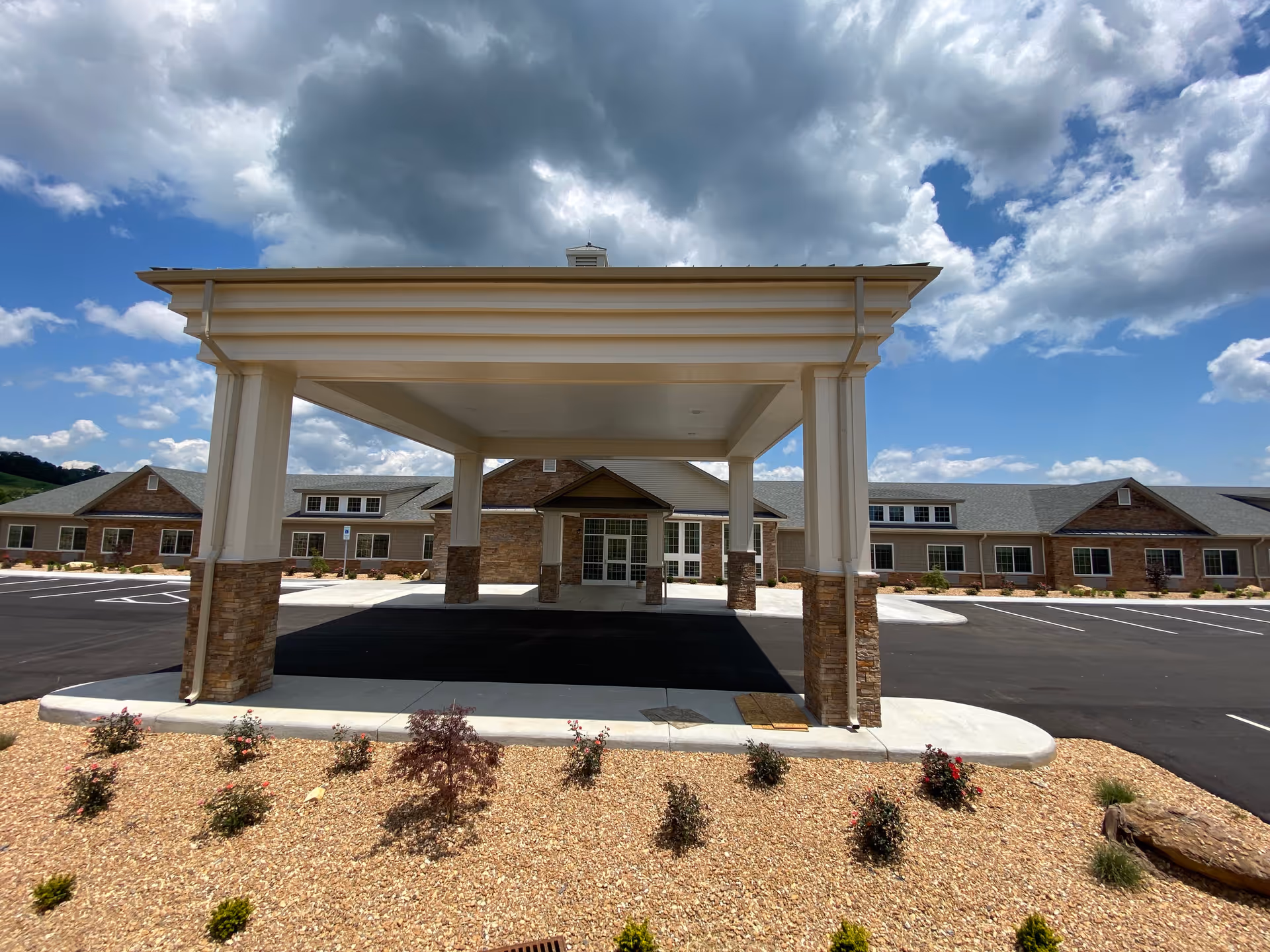 Exterior view of a senior living facility entrance with a large covered drop-off canopy.