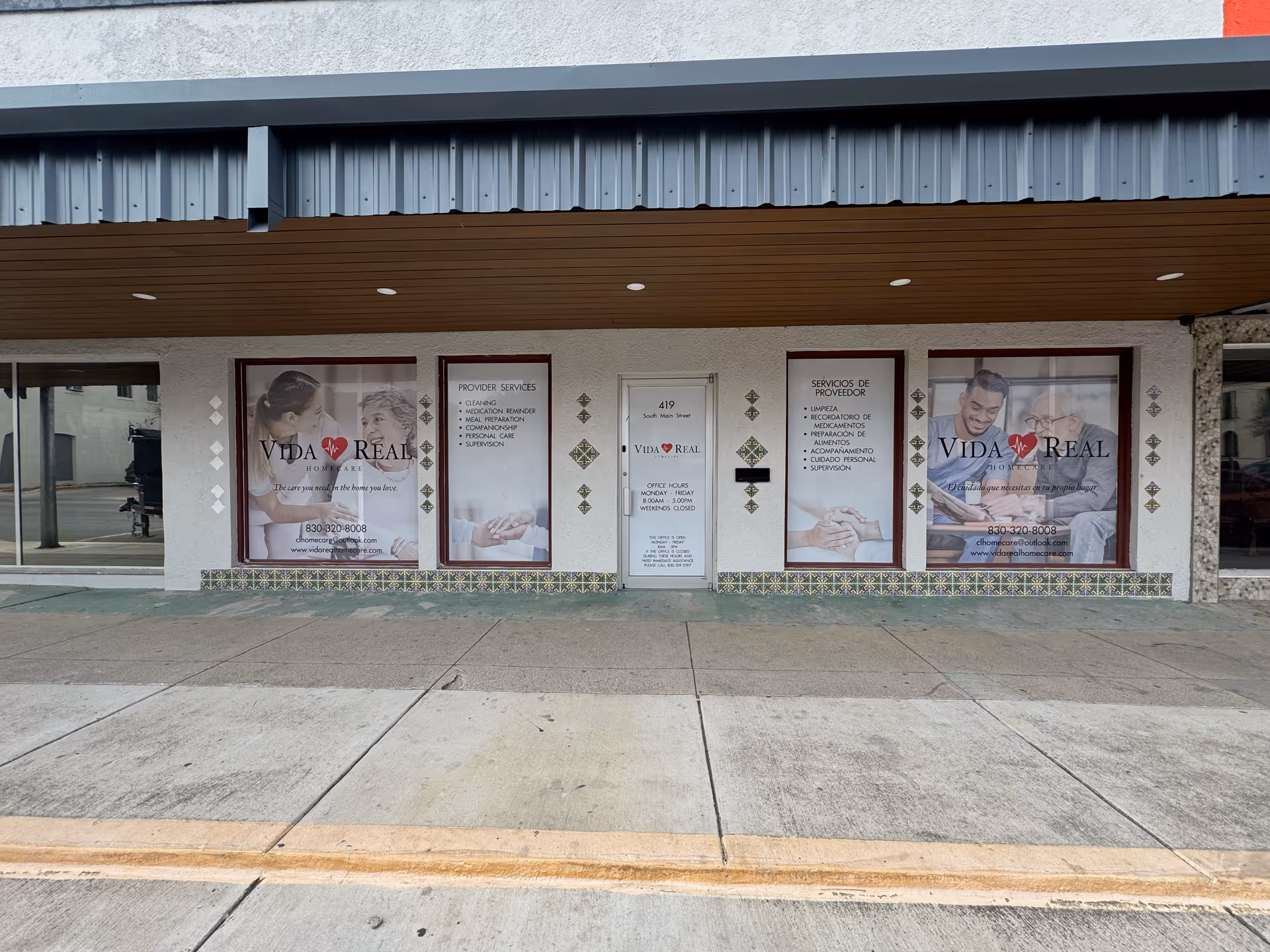 Storefront of Vida Real Home Care with large windows and framed service posters.