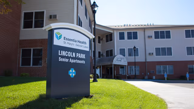 Exterior view of Lincoln Park Senior Apartments sign near a multi-story building.