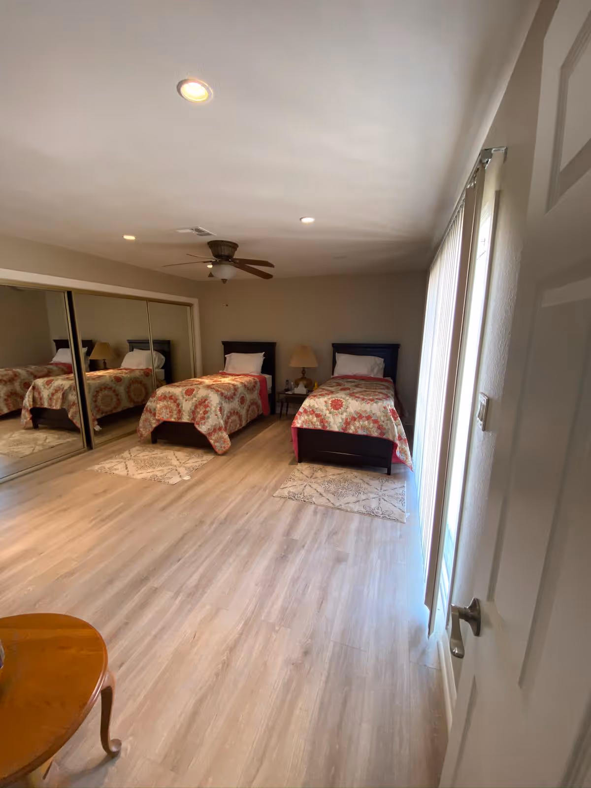 Two twin beds with matching quilts flank nightstands in a bright bedroom.