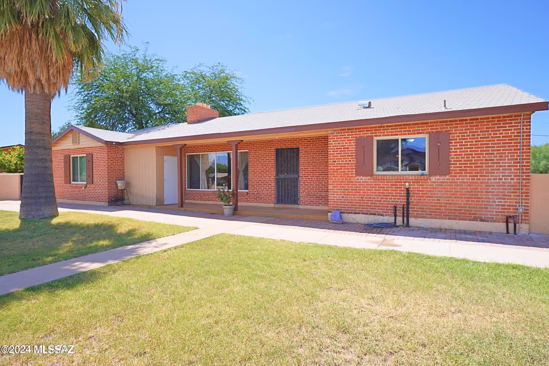 One-story brick building with front yard, palm tree, and entry walkway.