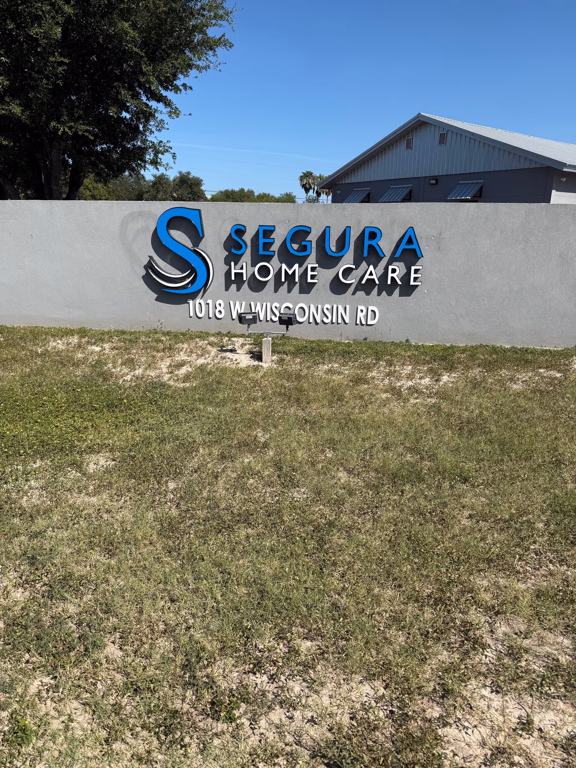Exterior view of Segura Home Care sign on a concrete wall in front of the building.