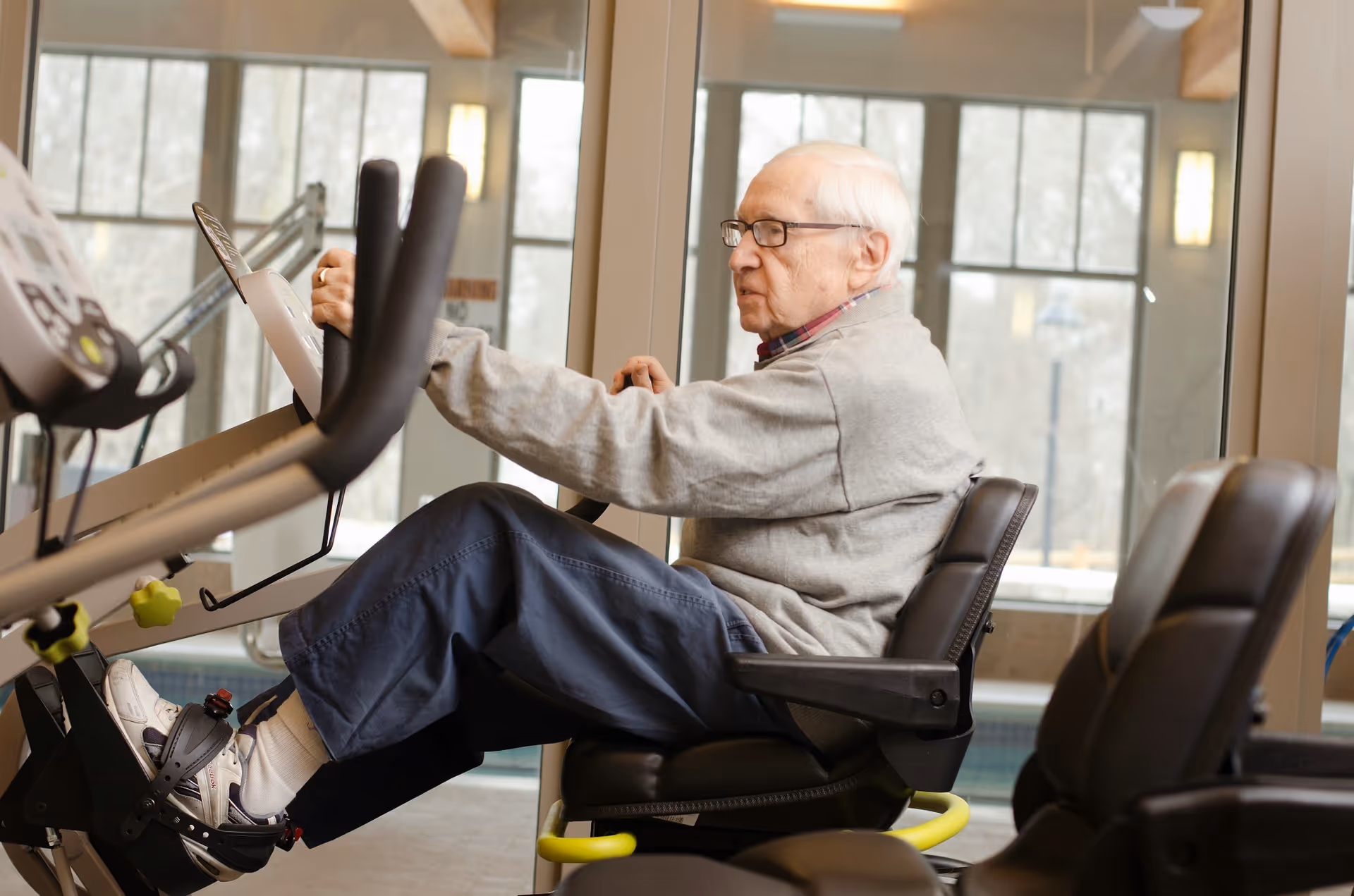 An elderly man exercises on a treadmill inside a modern Epoch senior living gym.