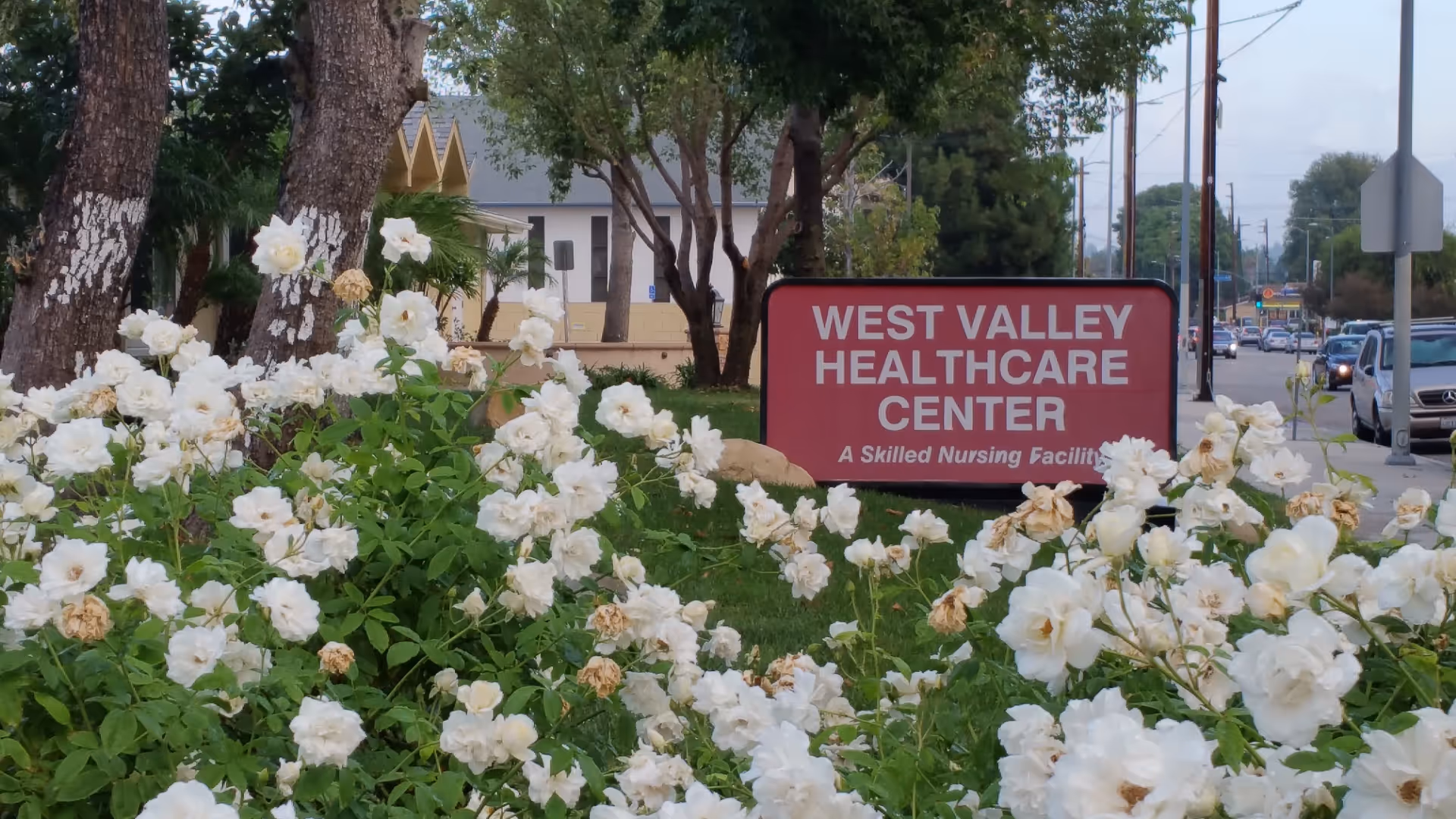 Exterior view of West Valley Healthcare Center with white roses in the foreground.