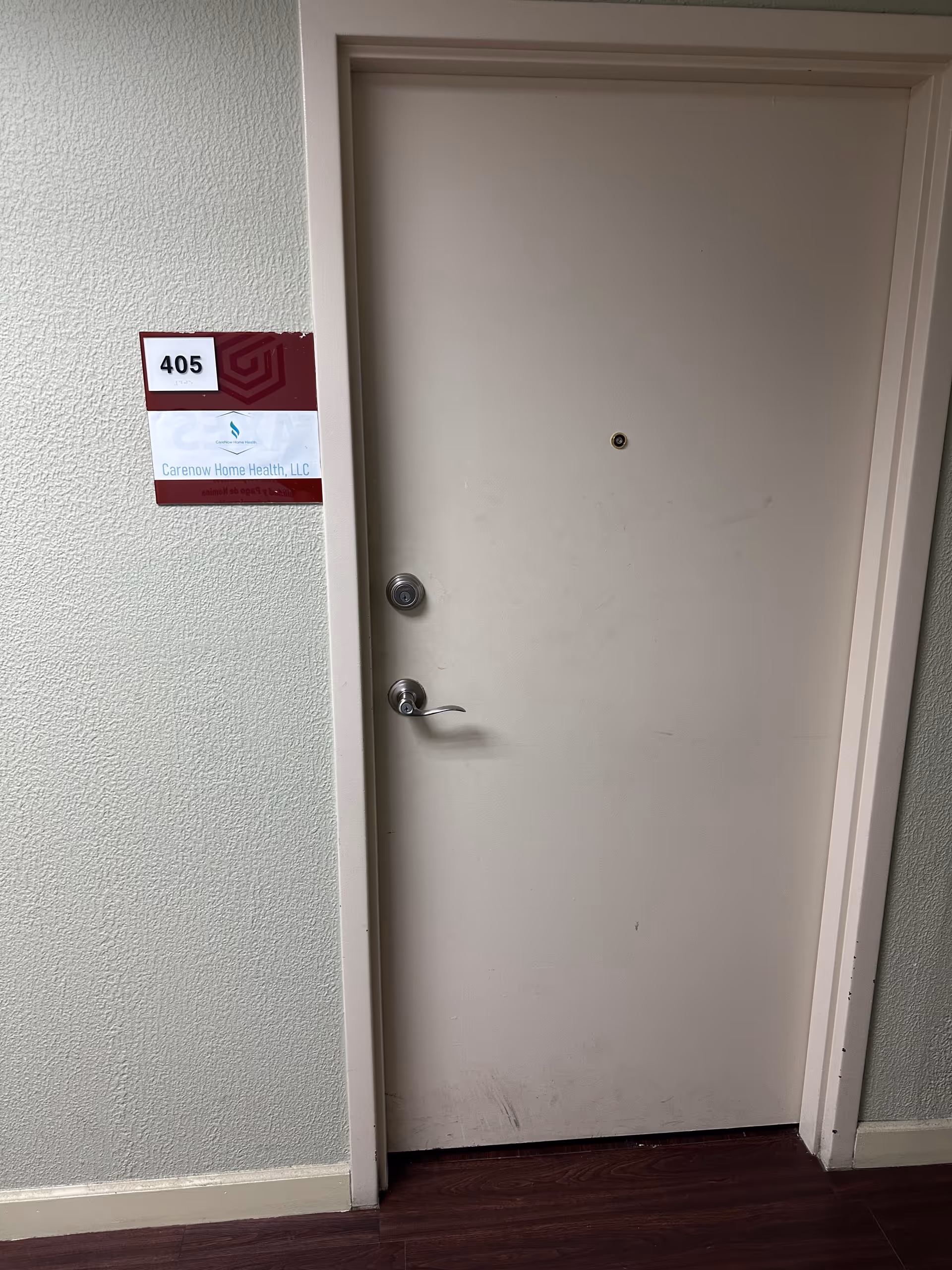 Beige interior door labeled 405 with CareNow Home Health LLC sign beside it.