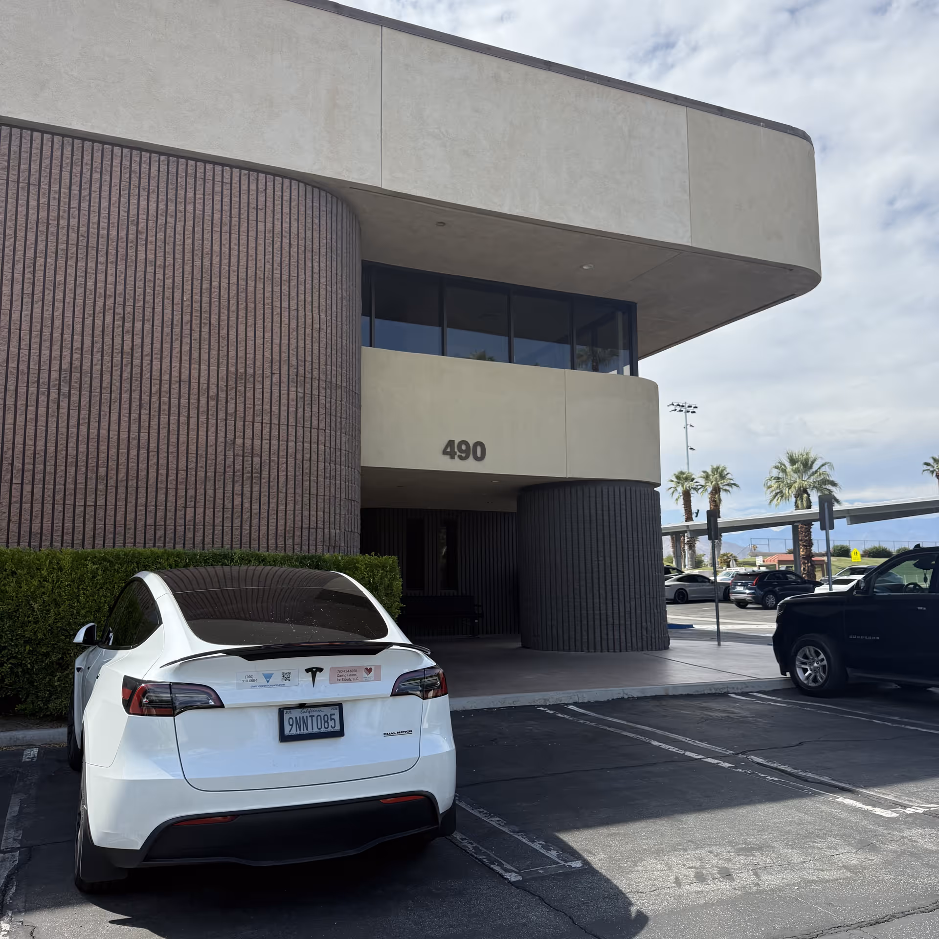Modern beige building with curved entrance, address 490, and parked cars.