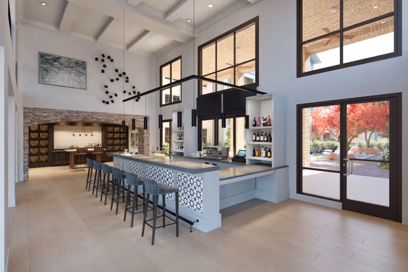 Bright modern bar and lounge area with a long counter, stools, and large windows.