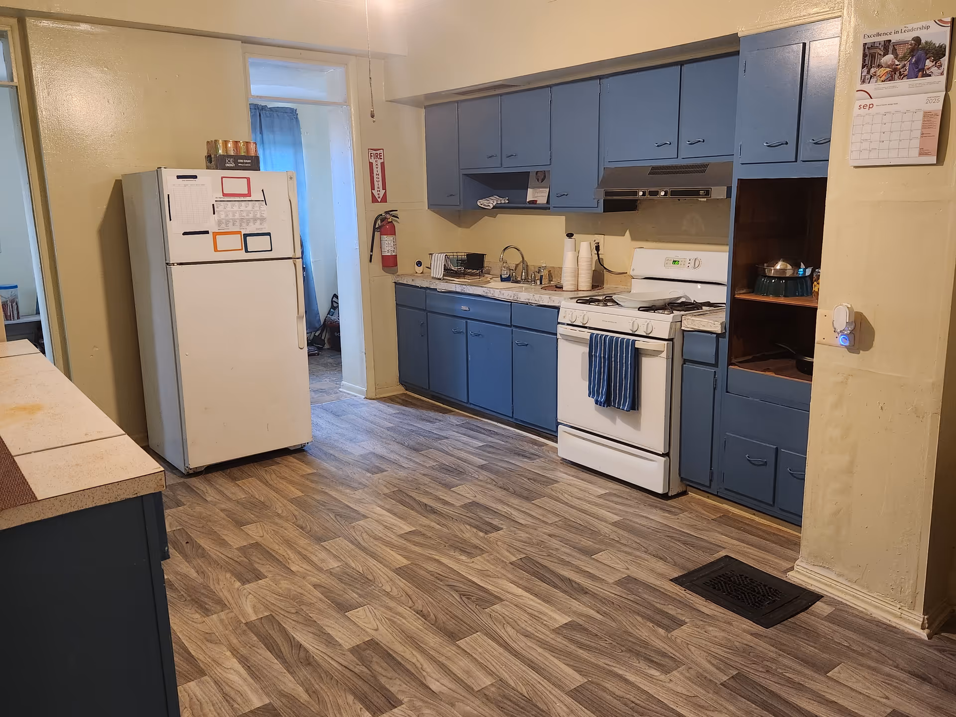 Blue kitchen with blue cabinets, a white refrigerator, and a stove along a counter.