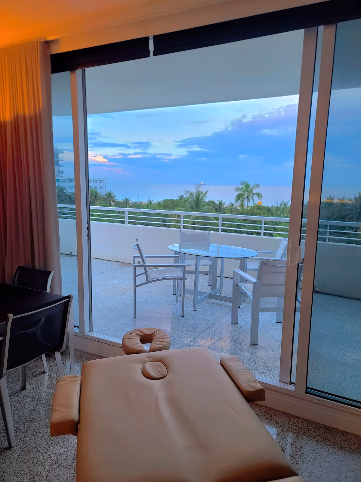 A massage therapy table inside a room with a sliding glass door to a balcony.
