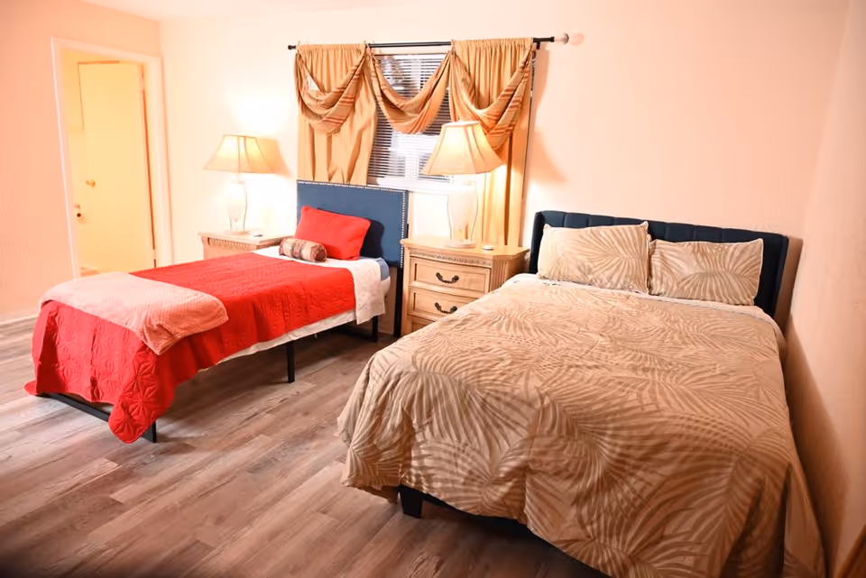 Two beds with different bedding and nightstands in a cozy bedroom.