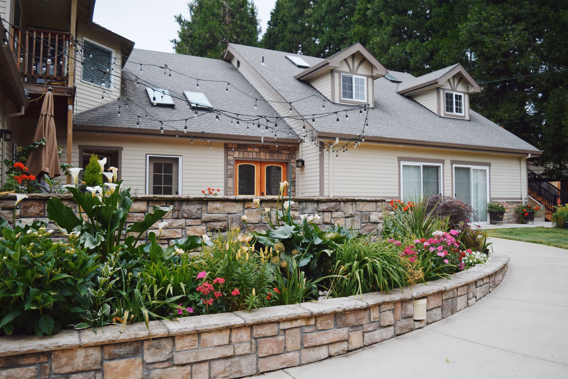 Vineyard Home Senior Living exterior with stone planter bed and string lights along the entrance.