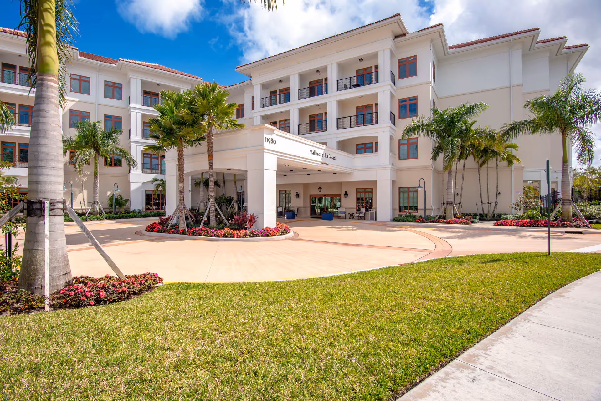 La Posada senior living facility exterior with a welcoming entrance and tropical landscaping.