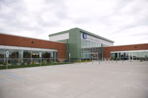 Exterior view of a modern medical clinic with a green entrance and large windows