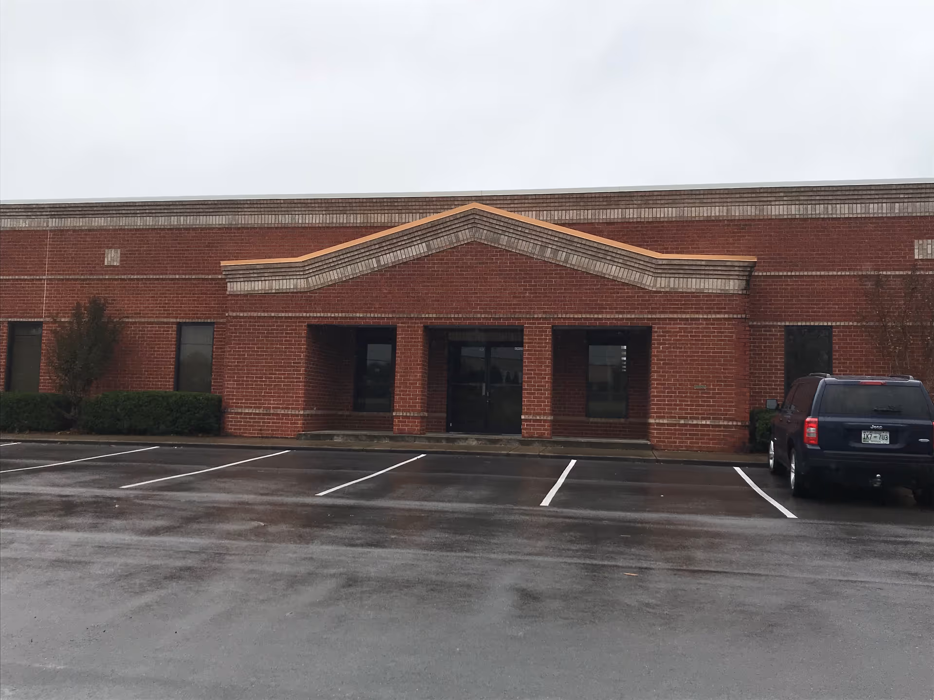 Brick exterior of Aveanna Home Health building with a wet parking lot in front.