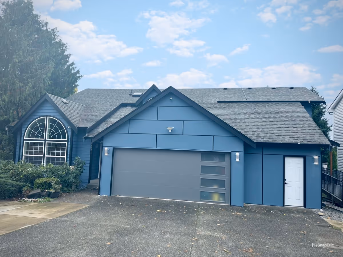 Blue single-story building with a large garage door and a white entry door.