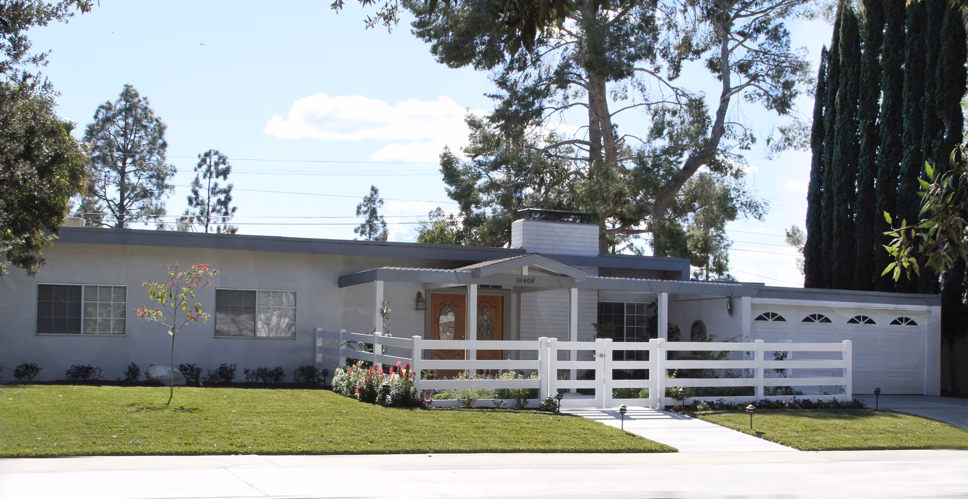 Single-story senior care facility with a white fence, tidy lawn, and driveway