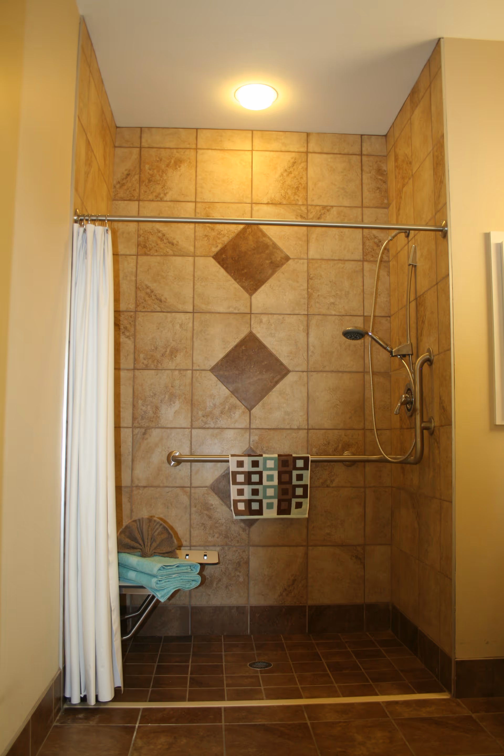 Enclosed tiled shower area with curtain, grab bar, and neatly folded towels.