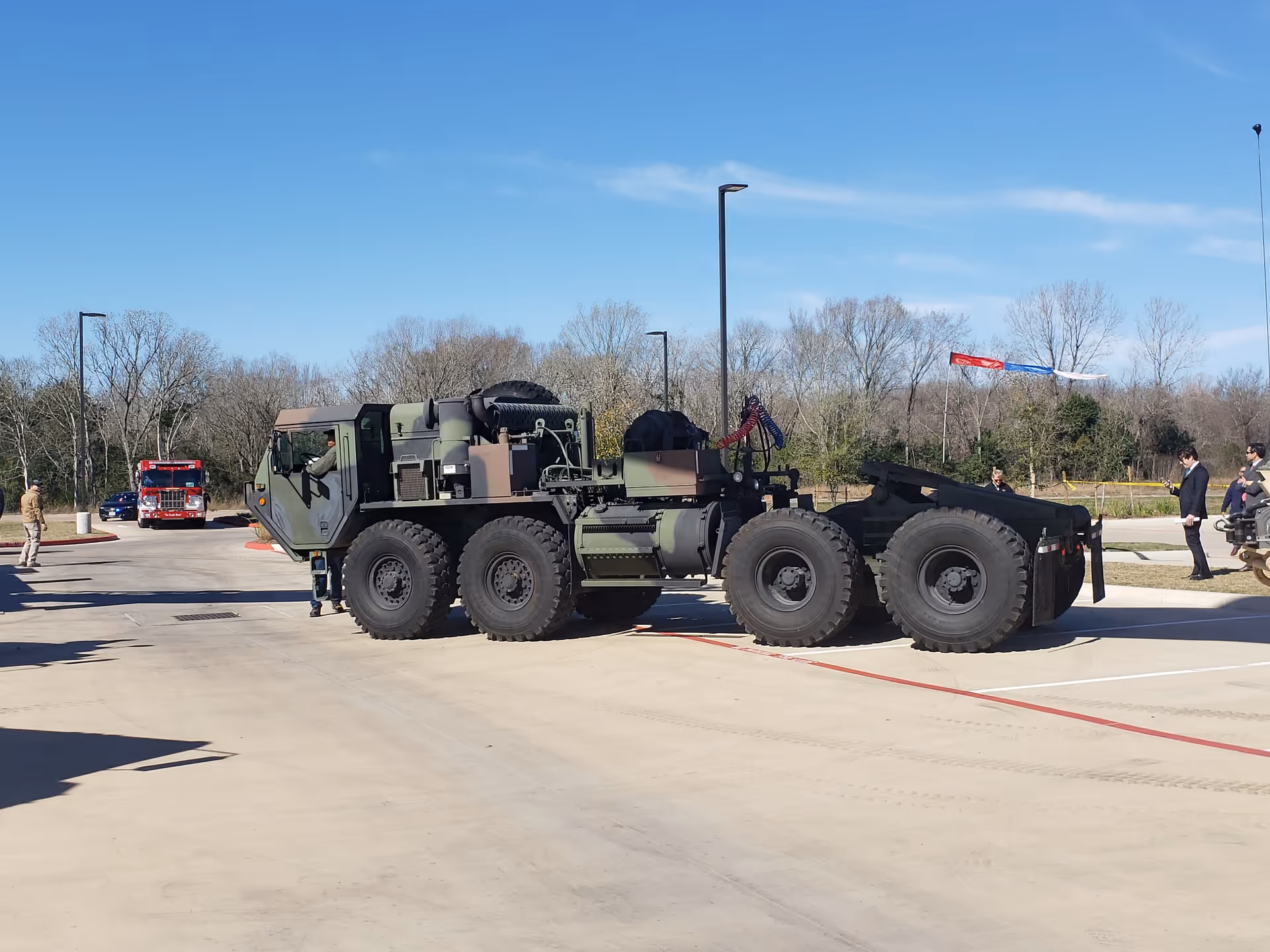 A large multi-axle military vehicle parked in a paved lot near a veterans home.