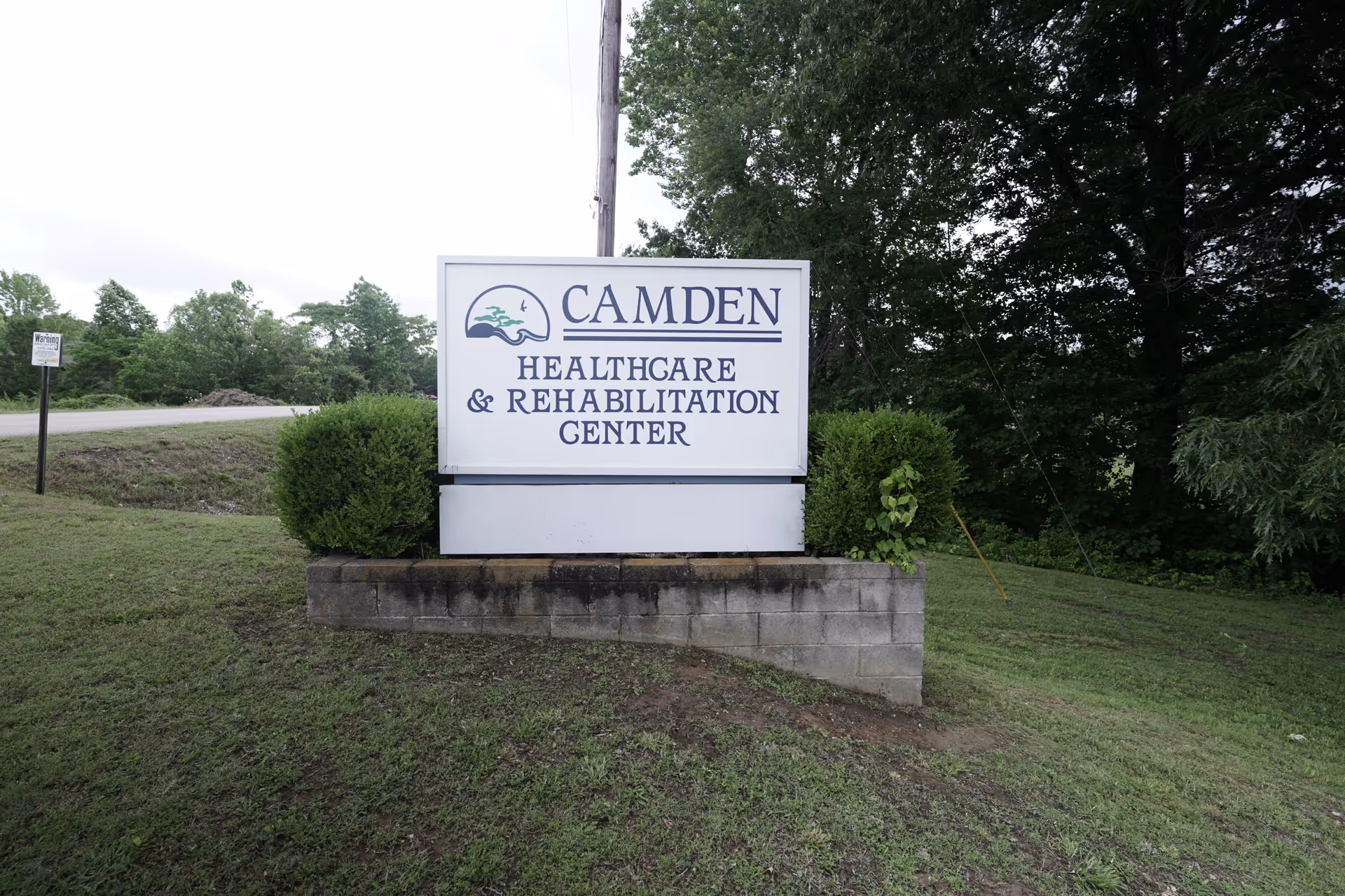 Outdoor sign for Camden Healthcare & Rehabilitation Center on a concrete pedestal with greenery