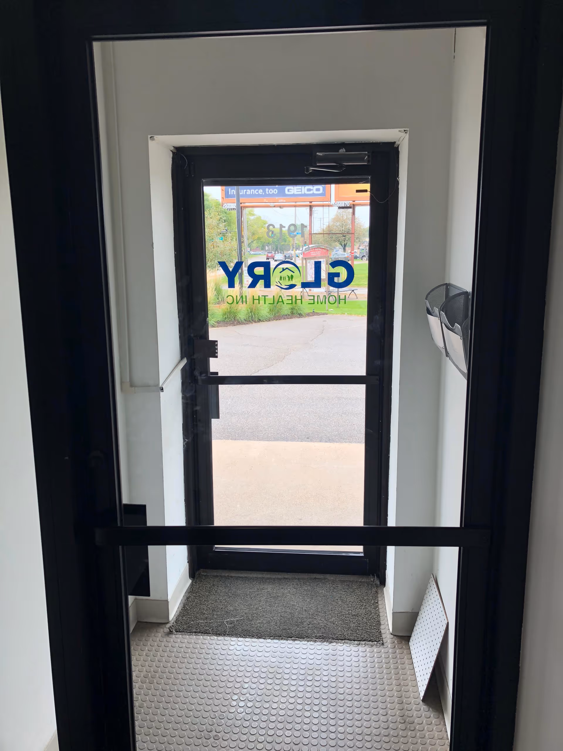 Interior entrance with glass door displaying Glory Home Health Inc; view of outside street.