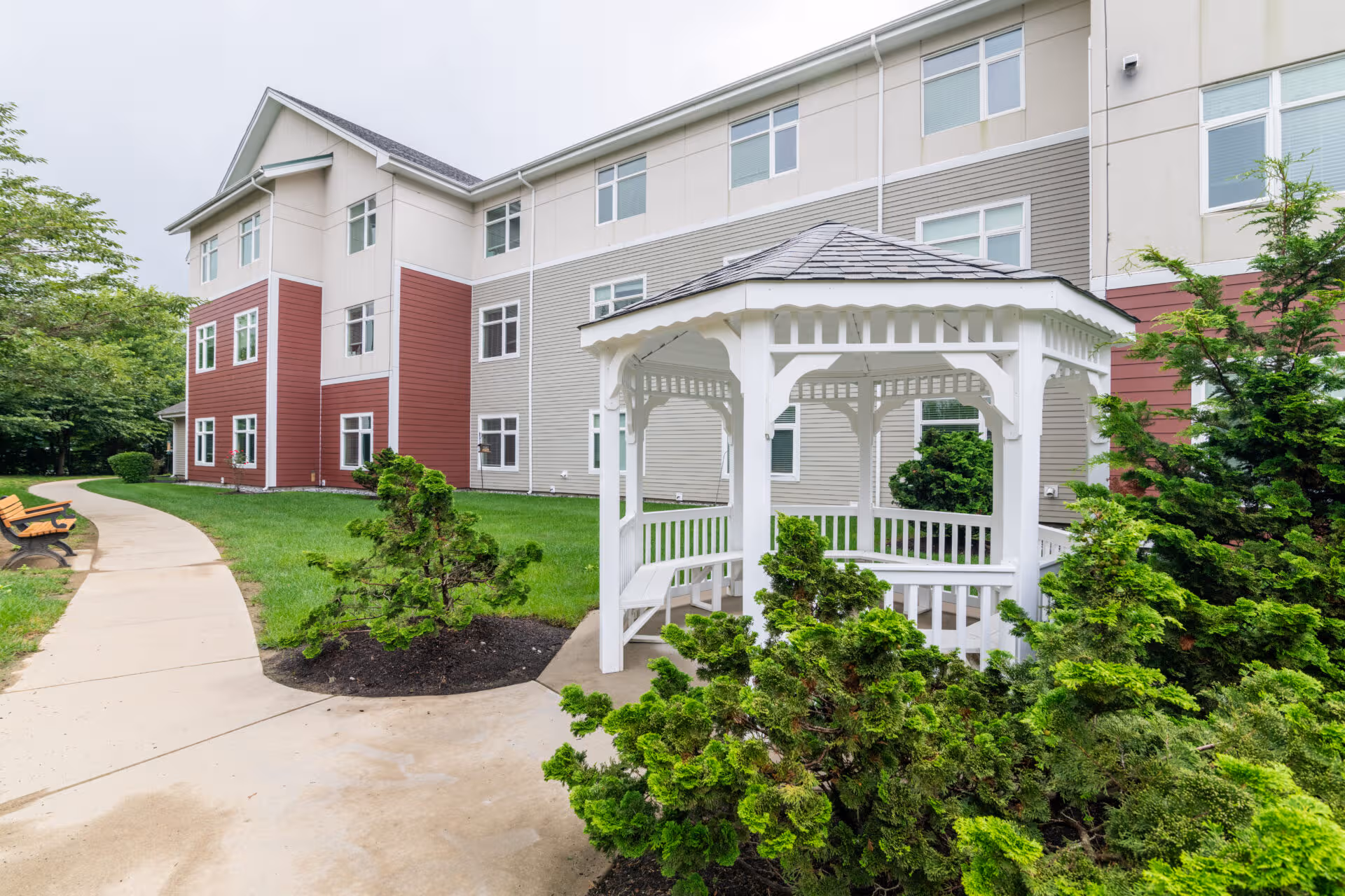 Exterior view of Benchmark Senior Living at Split Rock with a white gazebo and landscaped path.