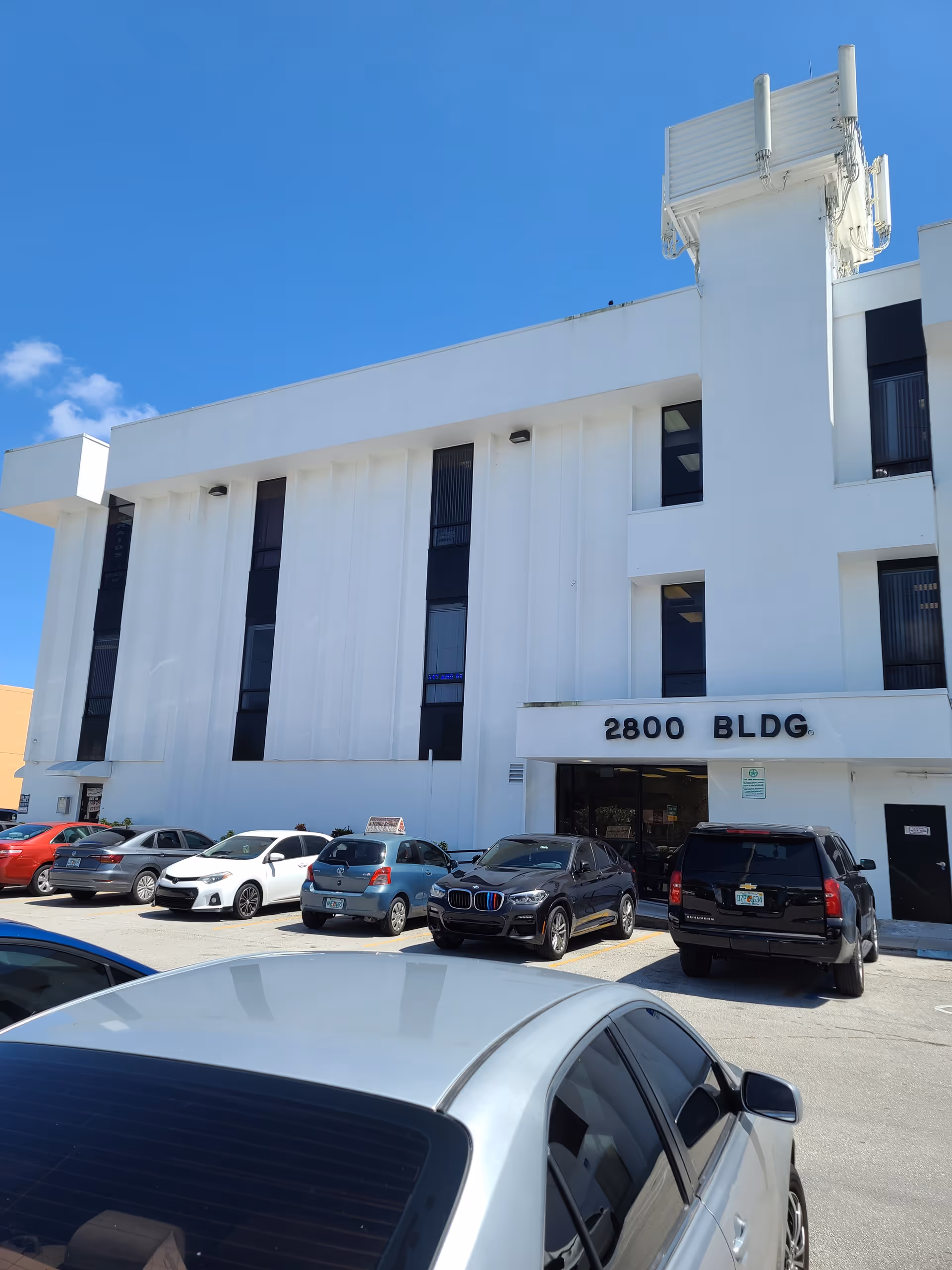 Senior living facility exterior with a white facade and parked cars.