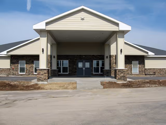 Exterior view of The Autumn Fields facility entrance with a stone facade and covered driveway.