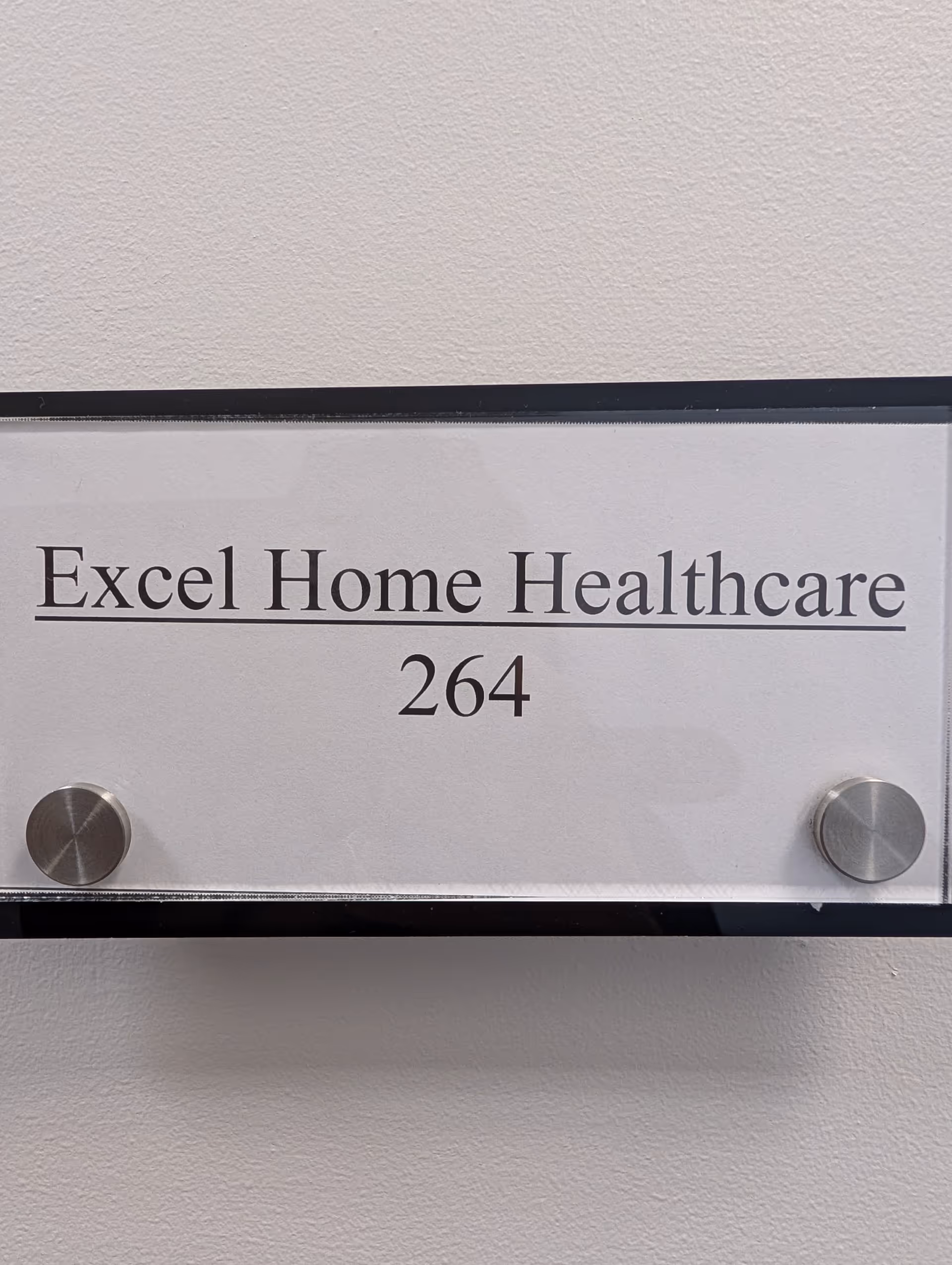 Close-up of a wall sign reading Excel Home Healthcare with number 264.