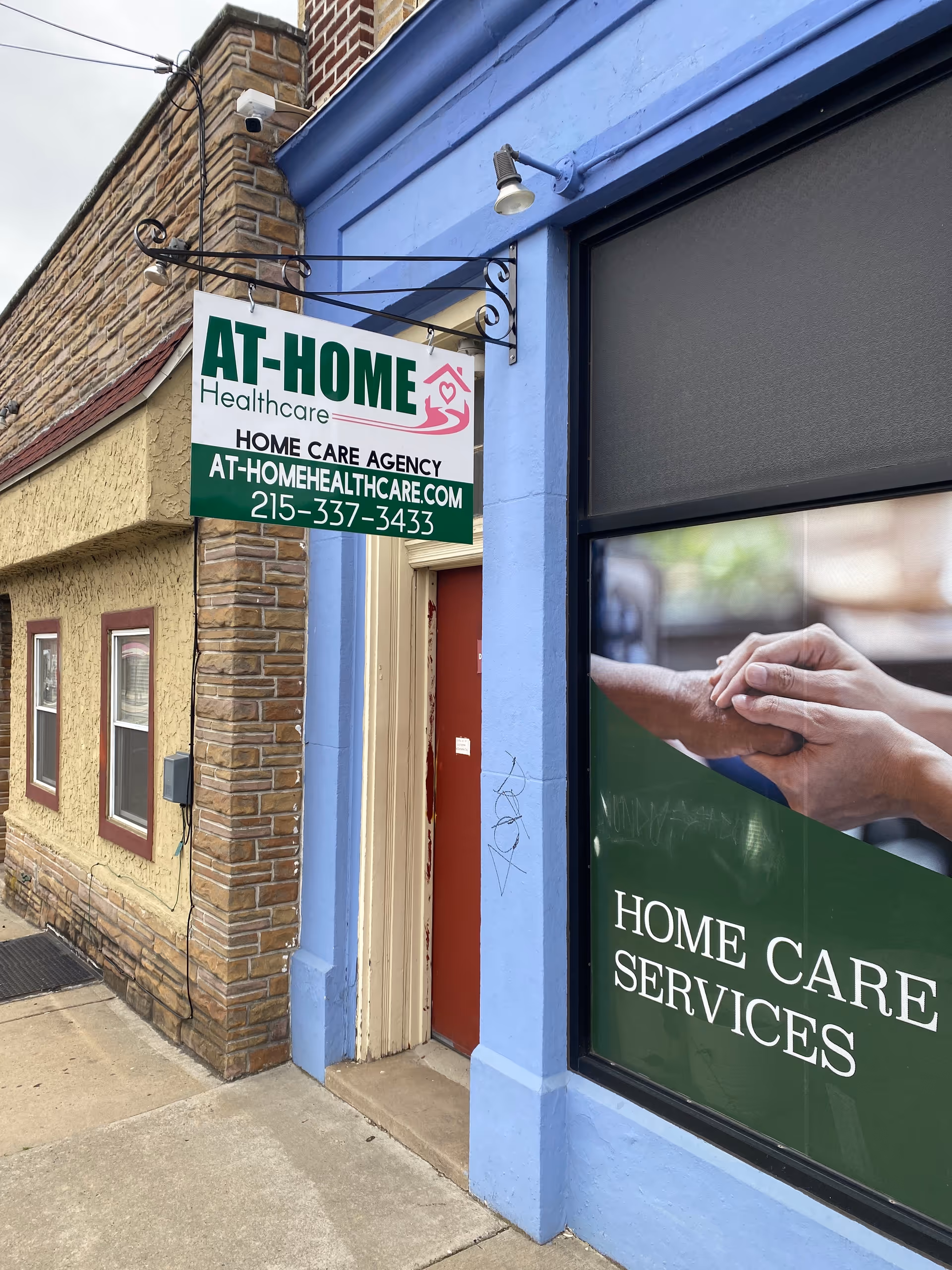 Exterior view of a storefront for At-Home Healthcare with sign and entrance.