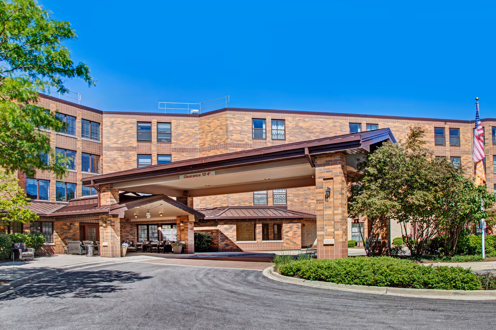 Exterior view of Sunrise of Park Ridge senior living facility with a covered entrance and landscaping.