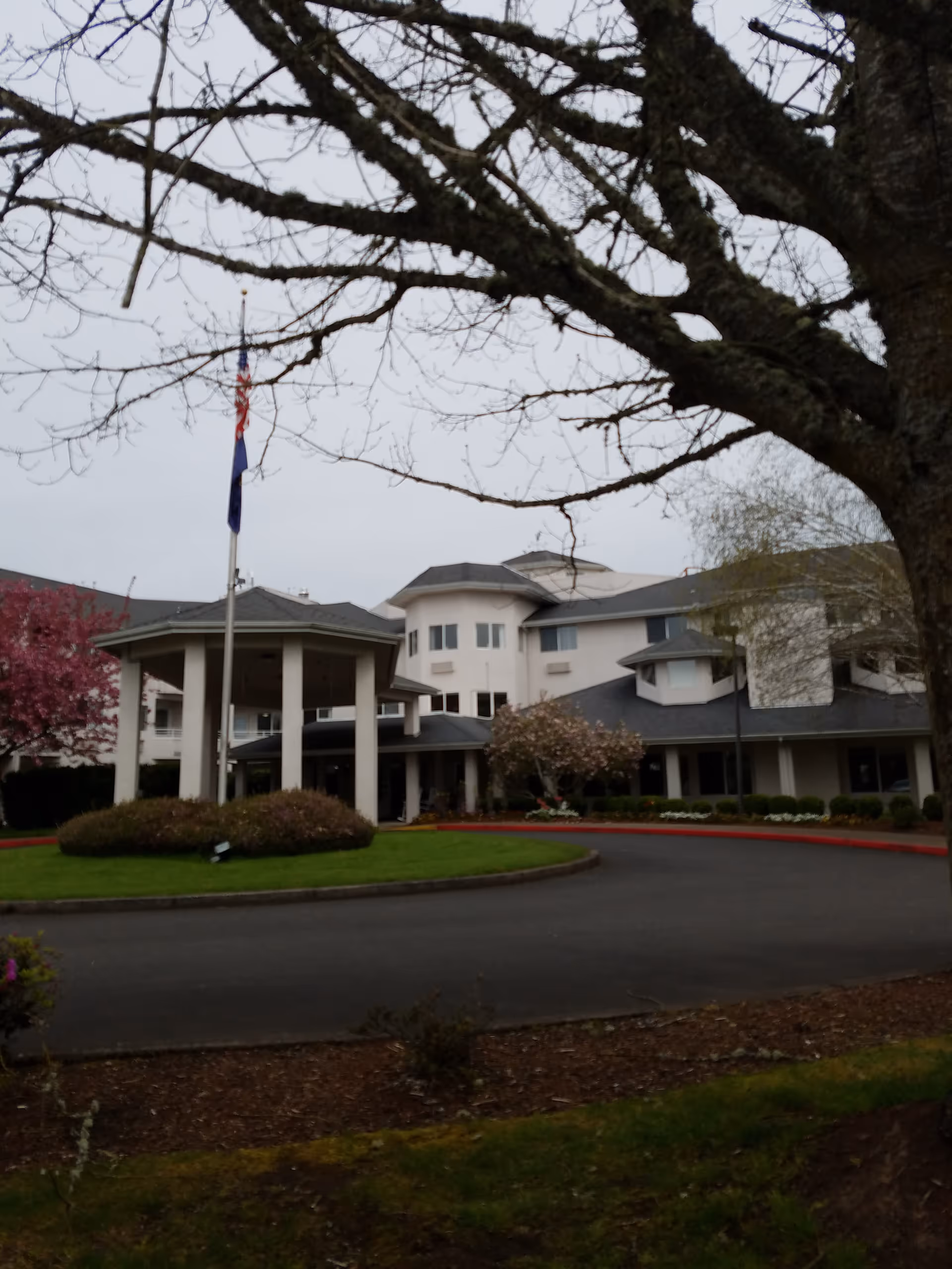 A large senior living facility with a circular driveway and front entrance under a canopy.
