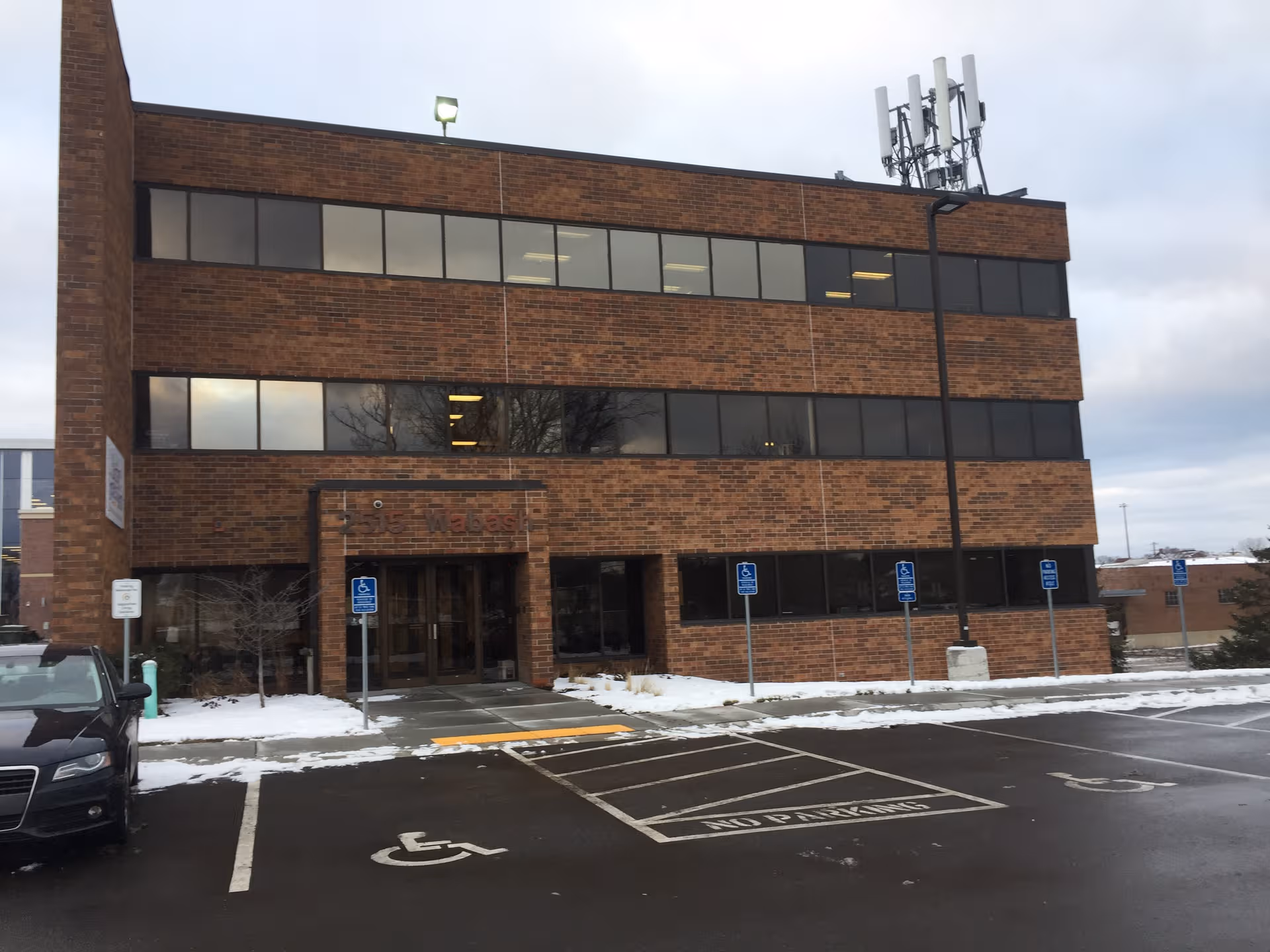 Three-story brick building with large windows and a snow-covered parking lot
