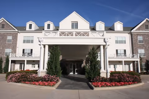 Front view of Prestonwood Court senior living facility with main entrance and landscaped beds.