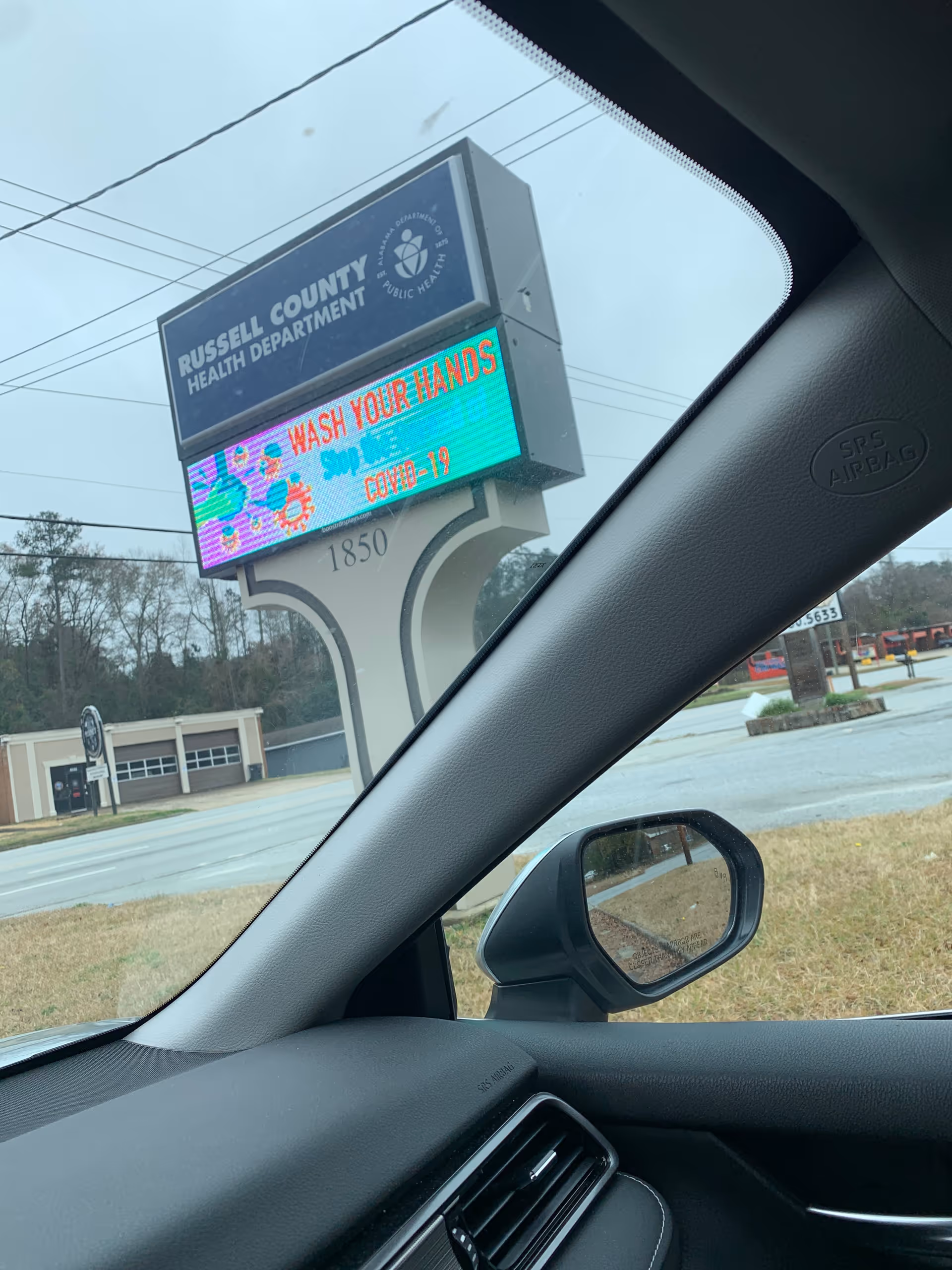 From a car, exterior Russell County Health Department sign displays 'WASH YOUR HANDS' COVID-19 message.