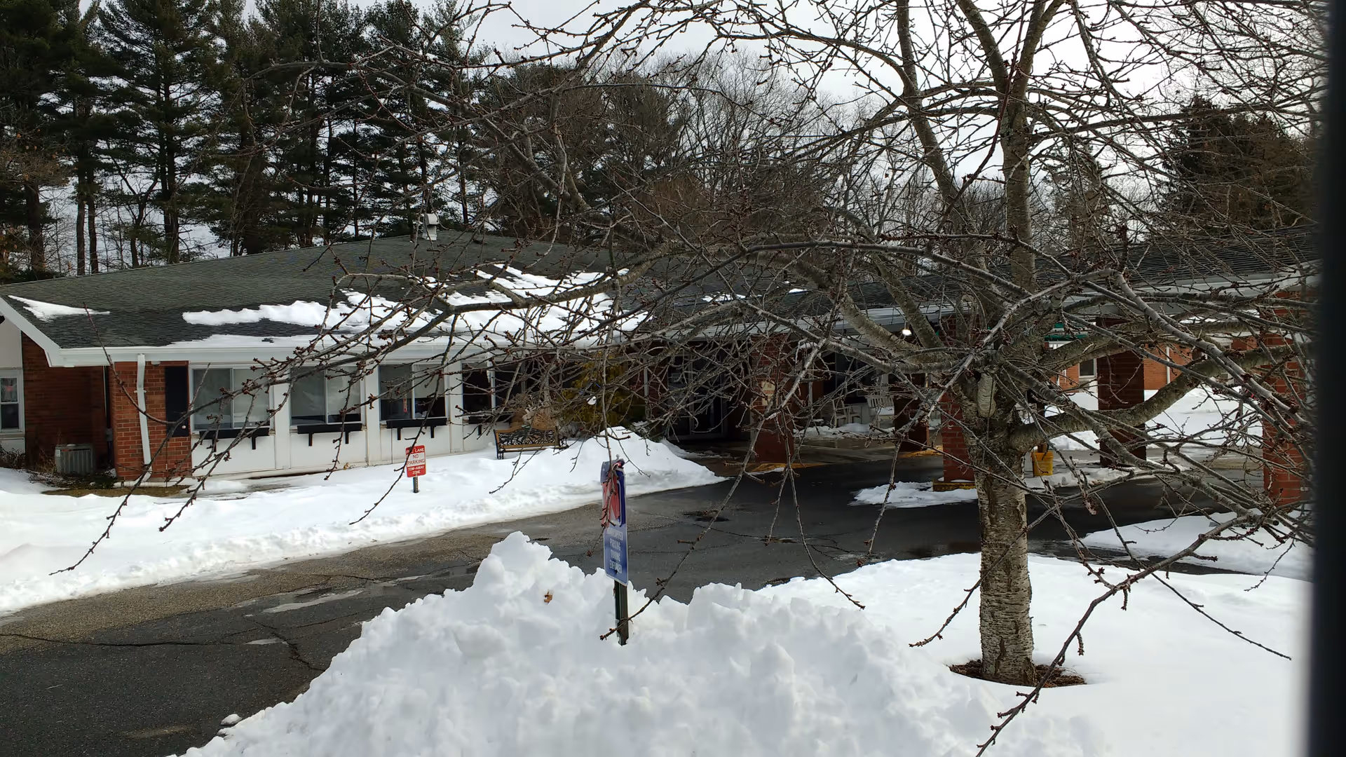 Exterior view of a brick senior living facility with snow and trees.