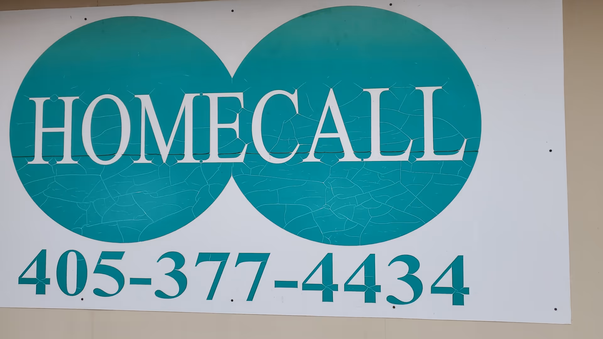 A large sign on a building exterior displaying HOMECALL and a phone number.