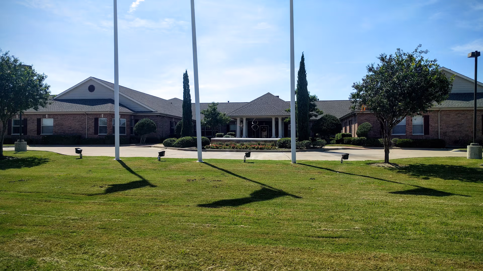 Exterior view of Grand Brook Memory Care of Carrollton featuring lawn and entryway.