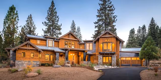A large wooden, modern-style senior living facility exterior with stone accents and trees.