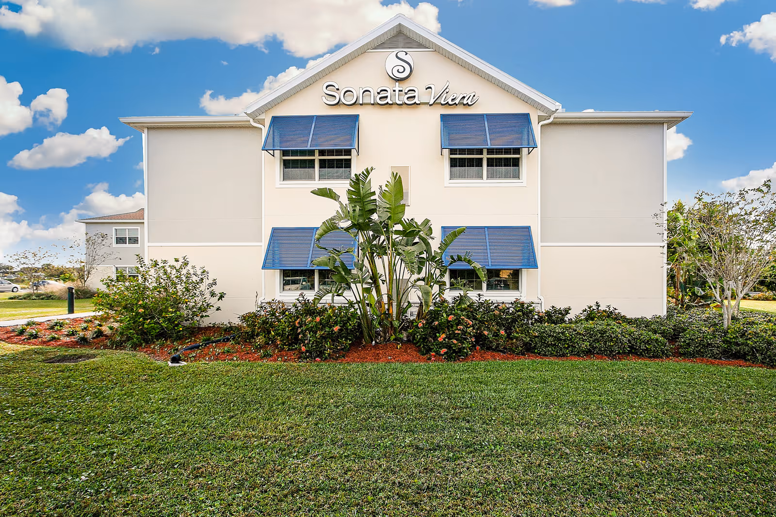 Exterior view of Sonata Viera building with blue awnings and landscaped lawn.